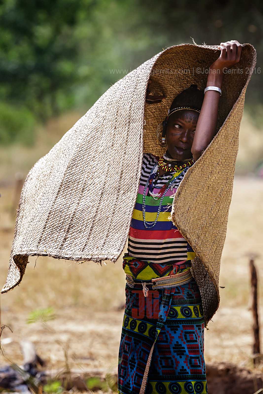 A young Bororo woman cleaning the braided mat